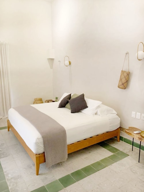 Dormitorio luminoso en Casa tuch de Mérida con cama de madera, ropa de cama blanca y decoración minimalista