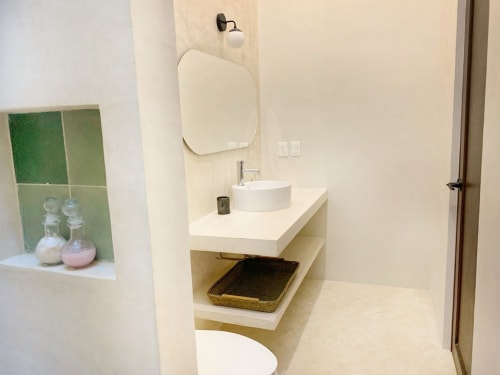 Baño moderno en Casa Tuch BnB en Mérida con lavamanos blanco, espejo redondo y diseño minimalista