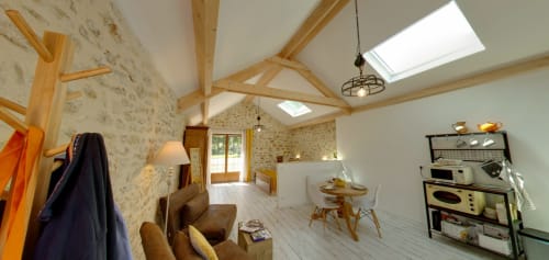 Spacious loft-style bedroom at Aux Prés Du Berry B&B with exposed beams, skylights, and wood accents in Chavin, France