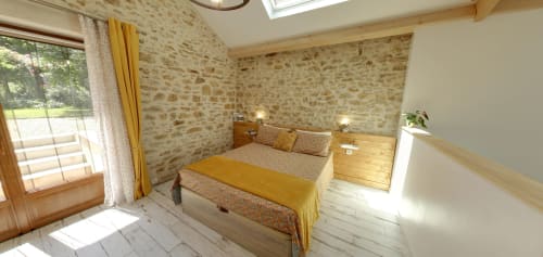 Bright bedroom at Aux Prés Du Berry B&B in Chavin, France with stone walls, wooden bed, yellow accents, and garden views