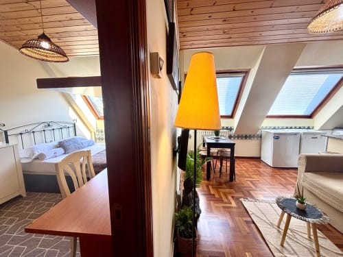 Acogedor apartamento en ático de Holibai en Baiona con lámpara amarilla, vigas de madera, tragaluces y muebles modernos
