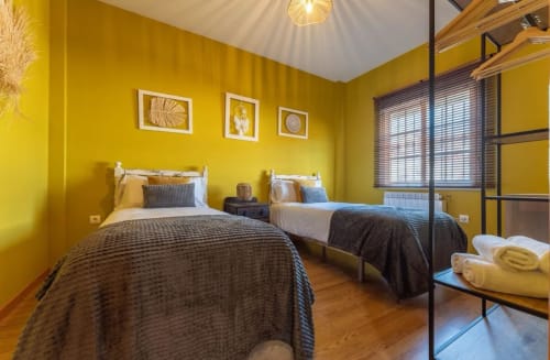 Habitación amarillo brillante con dos camas individuales en la casita Gestyp-AT de Mérida, España