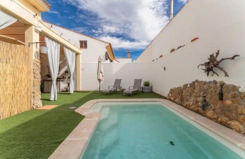 Área de piscina de la casa rural Gestyp-AT en Mérida con piscina turquesa, tumbonas y patio de muros blancos
