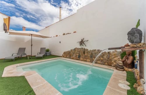 Piscina turquesa con tumbonas en patio soleado de la casa rural Gestyp-AT en Mérida, España