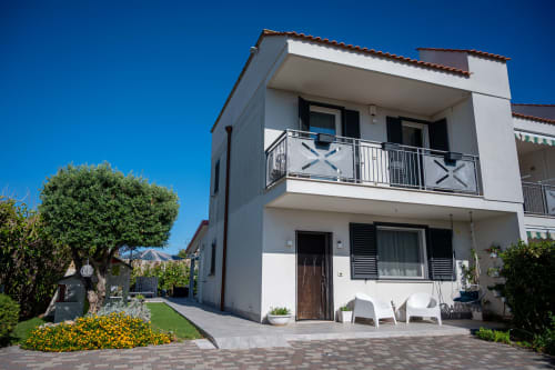 Modern white villa with terracotta roof in Ferrara, Italy featuring balconies, manicured gardens and patio area