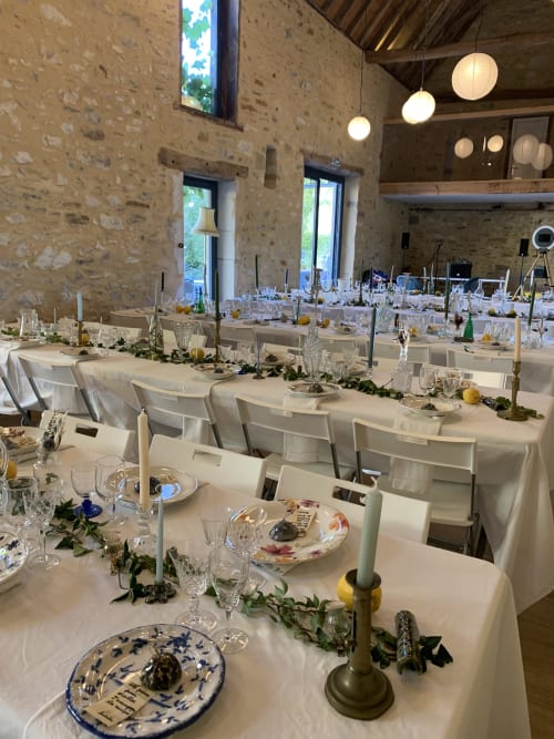 Élégante salle à manger du Château de Baylac avec tables dressées, lin blanc, chemins de verdure et ambiance aux chandelles à Bugnein.
