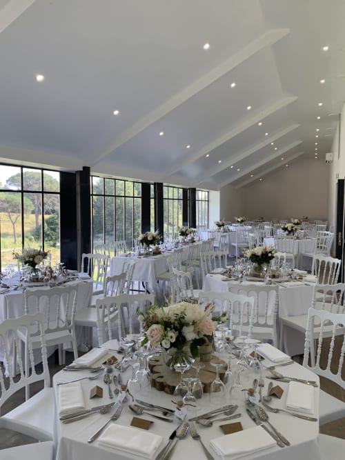 Élégante réception de mariage au Château de Baylac avec chaises blanches, compositions florales et vue sur les jardins