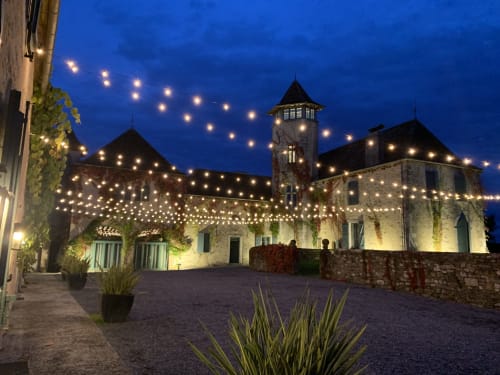 Château de Baylac au crépuscule, illuminé par des guirlandes lumineuses et projecteurs, Bugnein France