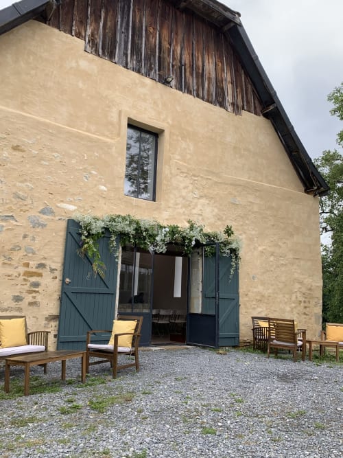Façade de la maison d'hôtes Château de Baylac en pierre de taille, portes vert foncé, volets en bois et coin terrasse