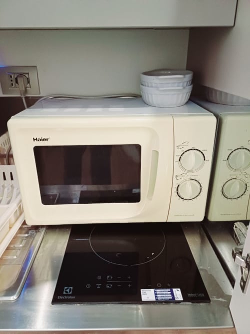 Microonde Haier bianco su piano cottura a induzione con manopole di controllo nella Michelangelo Suite Roma