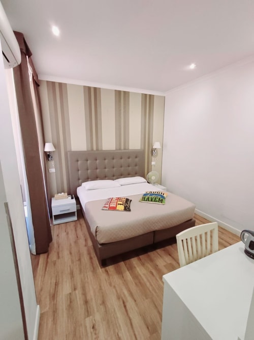 Camera moderna della Michelangelo Suite Roma con letto matrimoniale, testata a righe, parquet e arredi contemporanei