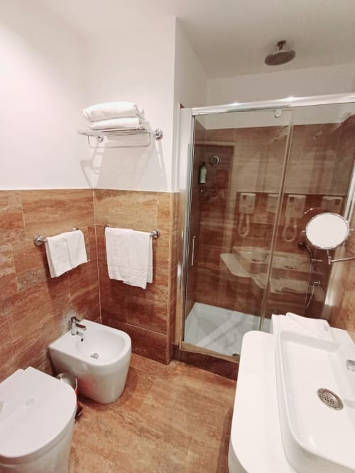 Moderno bagno della Michelangelo Suite Roma con pavimenti in terracotta, doccia walk-in, bidet e asciugamani bianchi