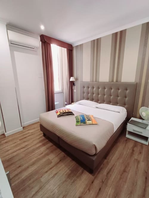 Camera moderna della Michelangelo Suite Roma con letto matrimoniale, carta da parati a righe, tende bordeaux e pavimento in legno