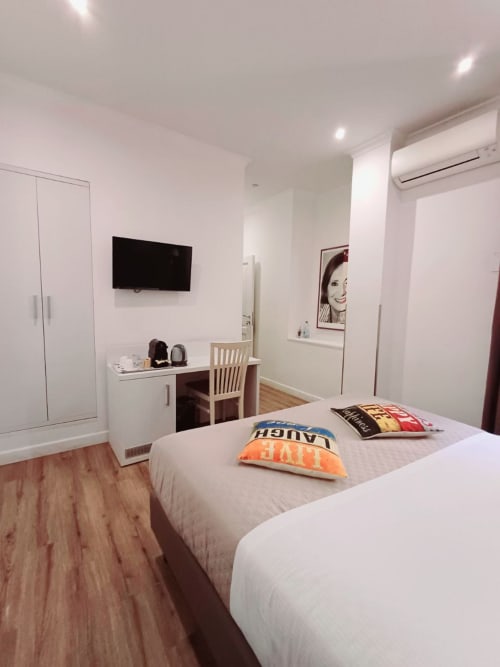 Camera moderna della Michelangelo Suite Roma con letto, TV a parete, scrivania, guardaroba e pavimento in legno