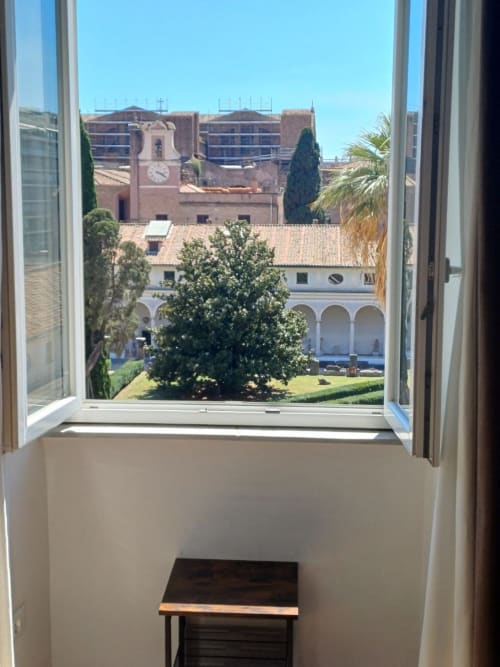 Vista dal giardino della Michelangelo Suite Roma con affaccio sulla corte, campanile e vegetazione lussureggiante