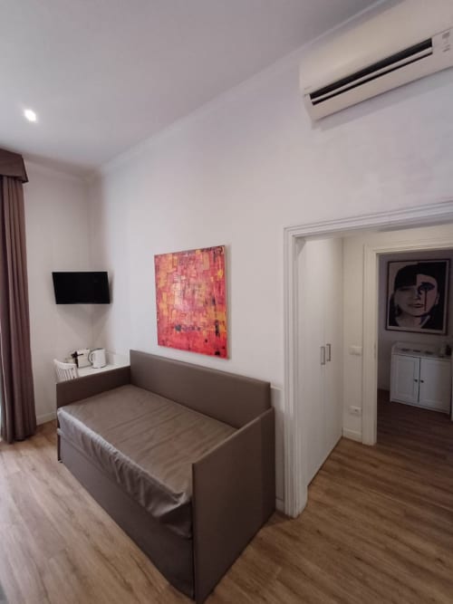 Camera moderna della Michelangelo Suite Roma con divano grigio, TV a parete e arte contemporanea nella B&B di Roma