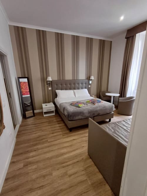 Camera da letto moderna presso Michelangelo Suite Roma con parete accent a righe, arredi eleganti e vista sul giardino