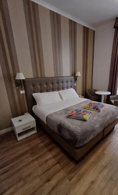 Letto king con cuscini bianchi e biancheria grigia a righe nella camera a tema della Michelangelo Suite Roma, hotel di Roma