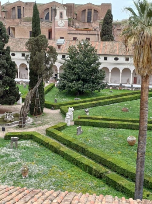 Il giardino del chiostro di Michelangelo a Michelangelo Suite Roma con siepi curate, cipressi e architettura rinascimentale