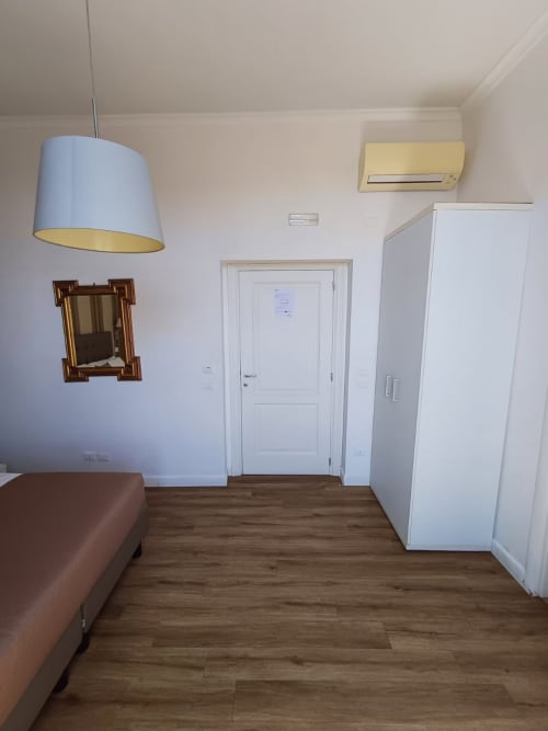 Camera doppia Michelangelo Suite Roma con pavimento in legno, armadio bianco, lampada a sospensione e climatizzatore
