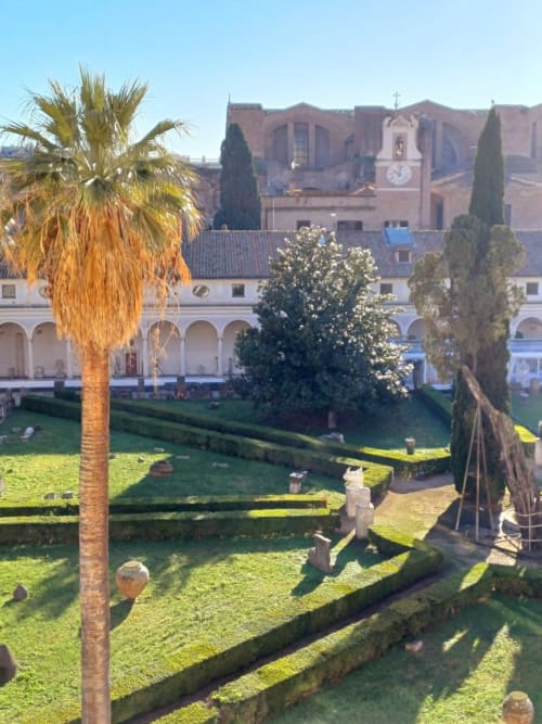 Chiostro Michelangelo con palma, cipressi e antichi edifici in terracotta presso Michelangelo Suite Roma