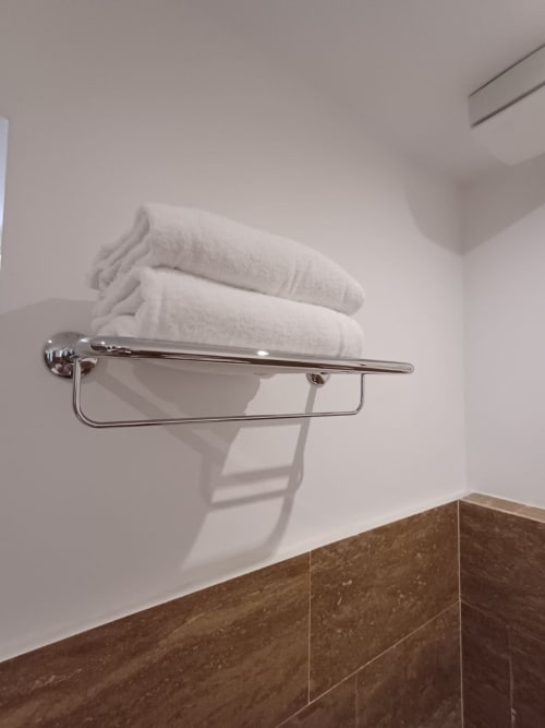 Porta asciugamani cromato con asciugamani bianchi soffici nel bagno moderno della Michelangelo Suite Roma hotel