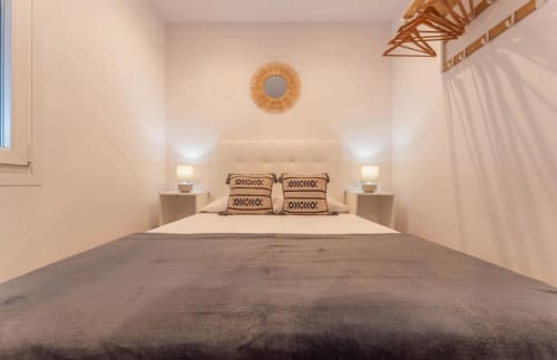 Moderno dormitorio en apartamento Gestyp-AT en Mérida con cama, decoración neutral, detalles en madera y ventana con vista a la ciudad