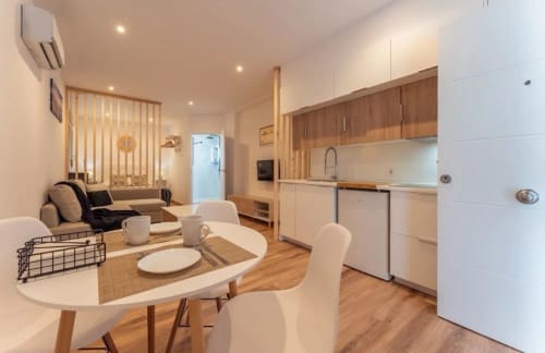 Apartamento moderno en Mérida con sala abierta, comedor con mesa redonda y cocina equipada con muebles de madera