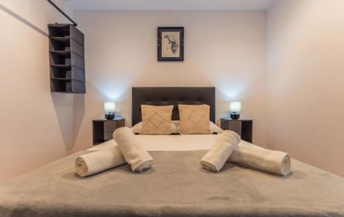 Moderno dormitorio en Mérida con toallas enrolladas, cabecero oscuro y vistas nocturnas de la ciudad