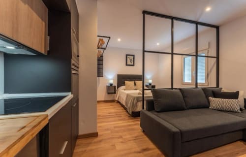Apartamento moderno en Mérida con sala de estar abierta, sofá negro, cocina y dormitorio separados por tabique de vidrio