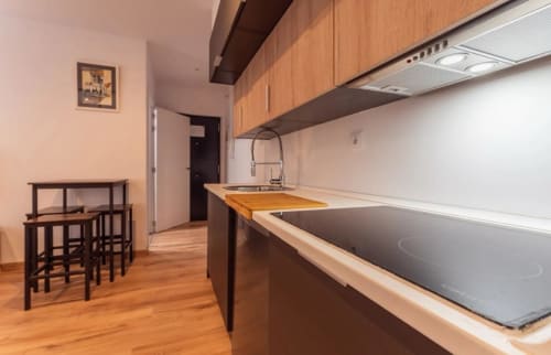 Moderna cocina de apartamento en Mérida con gabinetes de madera, estufa eléctrica y área de comedor con muebles de madera