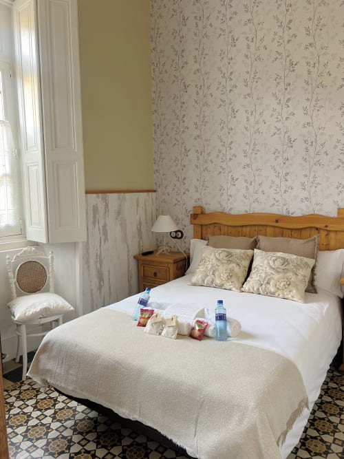 Cozy bedroom at La Venta de Miyares with wooden bed, floral wallpaper, welcome amenities, and traditional decor in Miyares,