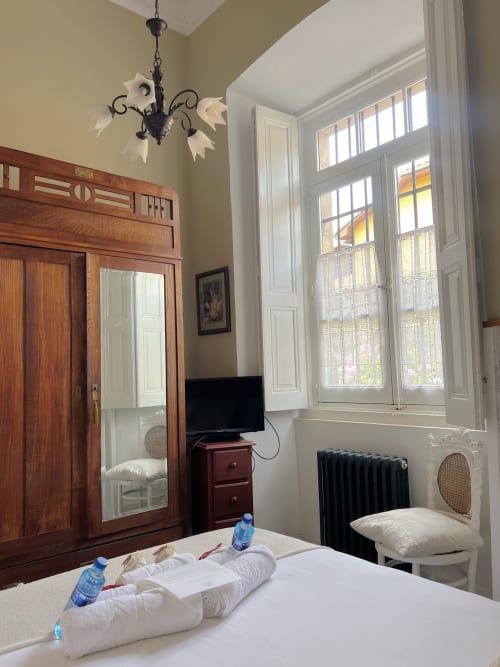Hotel room at La Venta de Miyares with wooden wardrobe, garden view windows, TV, and water bottles on bed