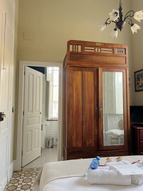 Bedroom at La Venta de Miyares with wooden wardrobe, cream bed, water bottle, and period furnishings in Miyares, Spain