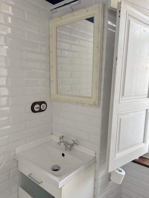 Modern white subway tile bathroom with framed mirror, pedestal sink, and chrome faucet at La Venta de Miyares hotel in