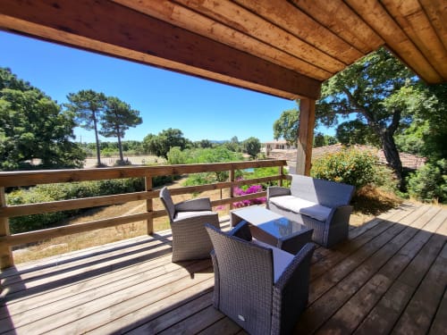 Wooden pergola deck at Villas Lantana in Lecci with rattan furniture, sea views, and flowering plants