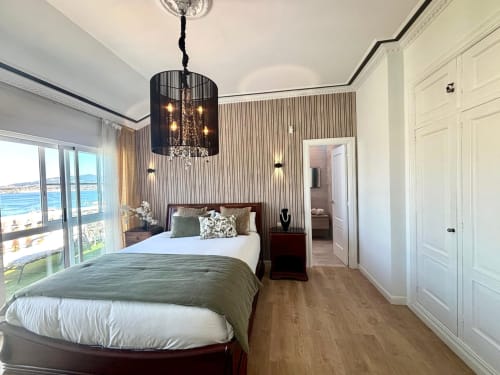 Habitación de lujo en Holibai Baiona con vistas al mar, lámpara de araña oscura, papel pintado a rayas y comodidades modernas