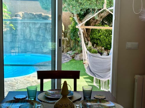 Elegante comedor con vistas a la piscina turquesa y jardín de la casa Serenidade en Baiona con vista al mar