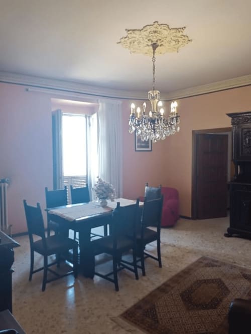 Elegante sala da pranzo dell'hotel Tales of Abruzzo di Atessa con lampadario in cristallo, sedie blu e pareti rosa