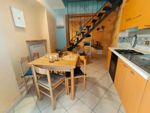 Cucina e sala da pranzo in arancione vivace presso Tales of Abruzzo ad Atessa con tavolo in legno, elettrodomestici moderni e scala