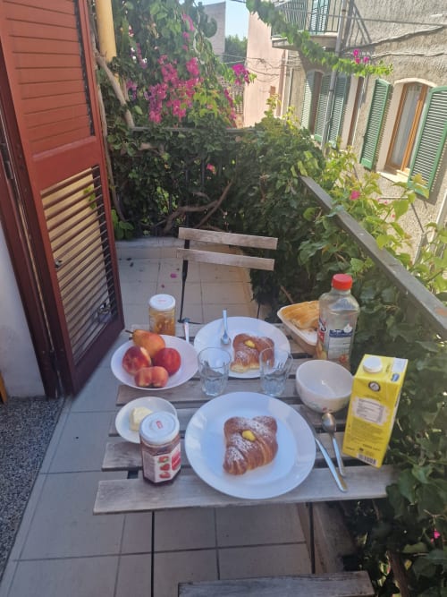 Breakfast table set on sunny terrace with pastries, fruit, and coffee at Casa Arborea apartment in Orosei