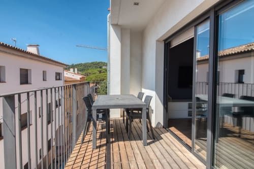Sunny terrace with dining table at Finques Garcia Enrich apartment in Palafrugell, overlooking town rooftops
