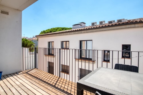 Sunny terrace with wooden decking and metal railings overlooking Calella, Palafrugell apartment with modern furnishings