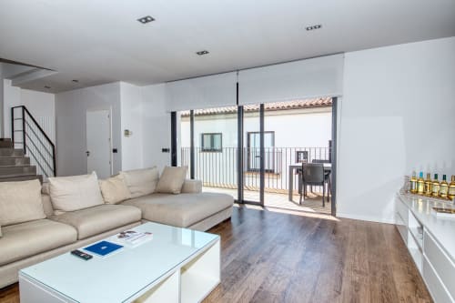 Modern duplex living room in Calella with beige sectional, white coffee table, and terrace access overlooking the