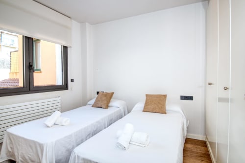 Twin bedroom in Finques Garcia Enrich apartment, Palafrugell with two single beds, brown cushions, white linens and window