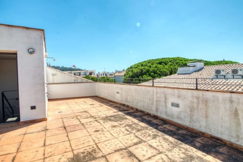 Rooftop terrace at Finques Garcia Enrich apartment in Palafrugell with terracotta tiles, ocean views, and forested hills.