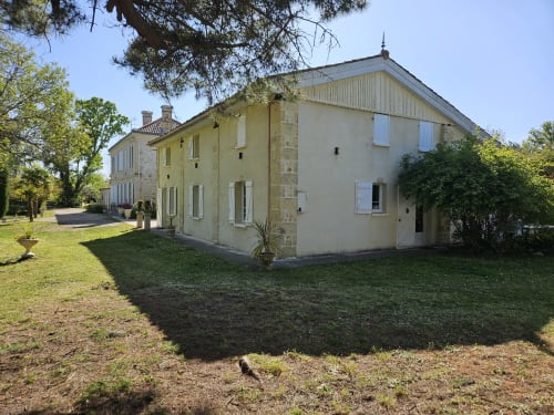 Le Manoir Lacustre Cottage Gîte mit Stein- und Crème-Fassade, umgeben von grünen Grünflächen und Bäumen in Queyrac, Frankreich