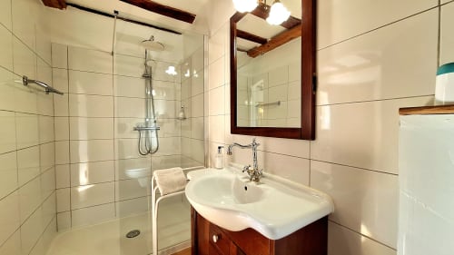 Salle de bain moderne de La Bergerie Du Moulin avec douche vitrée, lavabo blanc, meuble vasque en bois et murs carrelés