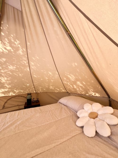 Intérieur douillet de tente glamping à Agritusmo Stecadò avec lit, oreillers et coussin blanc fleuri