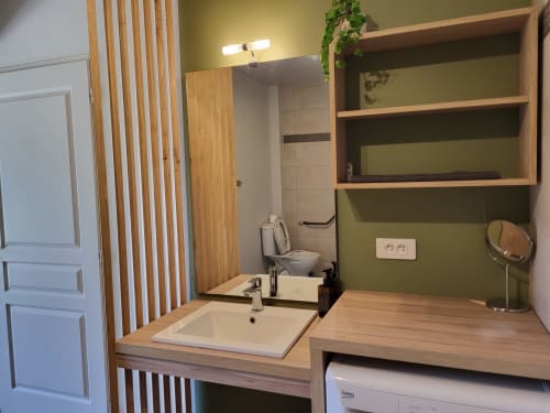 Modern bathroom at Villas Lantana in Lecci with wooden vanity, white sink, olive green walls, and wall-mounted shelving